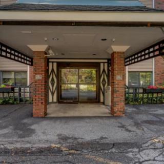 Entrance of a building with brick pillars and glass doors, surrounded by plants.