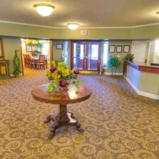 A hotel lobby with a central table adorned with flowers, surrounded by elegant carpeting and warm lighting.