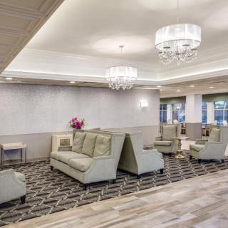 A modern lobby area featuring elegant sofas, chandeliers, and a patterned carpet.