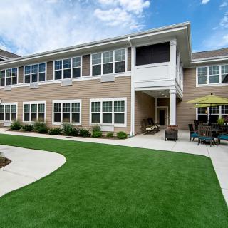A modern residential building with a well-maintained lawn and outdoor seating area.
