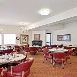 A spacious dining area with red chairs and set tables, ready for guests.