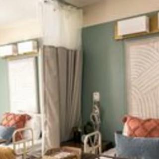 A modern living room with stylish decor, featuring a sofa, patterned pillows, and elegant curtains.