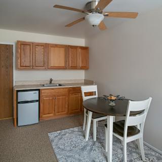 A cozy kitchen and dining area featuring wooden cabinets, a small table with chairs, and a ceiling fan.