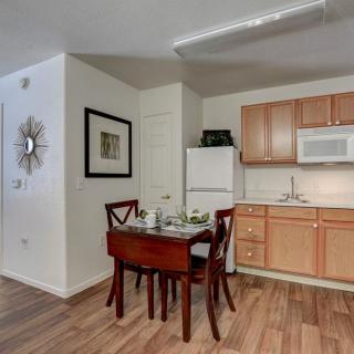 A cozy kitchen and dining area featuring a small wooden table with chairs, adjacent to a refrigerator and microwave.
