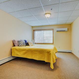 A minimalist bedroom with a yellow-bedded single bed and a window.