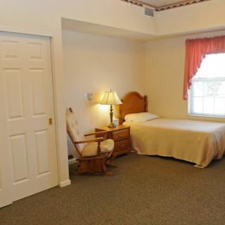 A cozy bedroom with a single bed, nightstand, and rocking chair.
