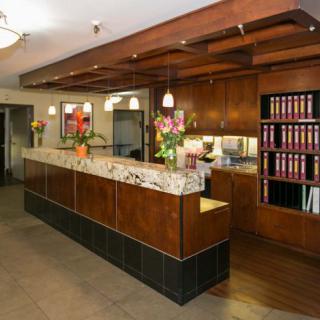 A well-organized reception desk in an office setting, featuring wood paneling and decorative flowers.