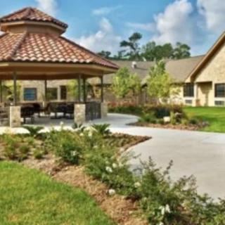 A beautiful garden with a gazebo and paved pathway leading to adjacent buildings.