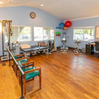 A well-equipped physical therapy room with exercise equipment and seating area.