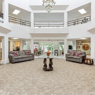 A spacious and luxurious living room with elegant furniture and a central chandelier.