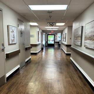 An empty hospital hallway with artwork on the walls and bright overhead lighting.