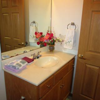 A neatly arranged bathroom vanity with a mirror, decorated with flowers and towels.