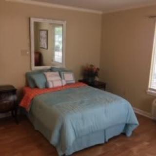 A cozy bedroom with a neatly made bed and a mirror above the headboard.