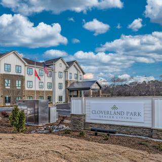 A residential building with a prominent entrance and sign under a partly cloudy sky.