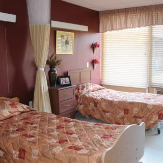 A cozy room with two beds and natural lighting from a large window.