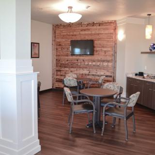 A cozy dining area with a wooden table, chairs, and a brick accent wall, featuring a mounted TV and modern lighting.