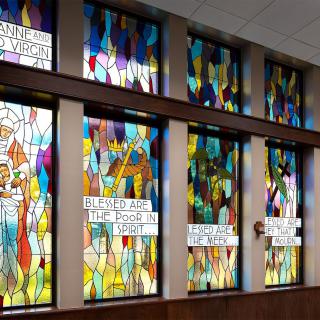 A series of colorful stained glass windows with abstract designs in a church setting.