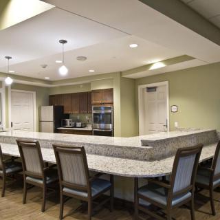Modern kitchen interior with a large counter and several chairs.