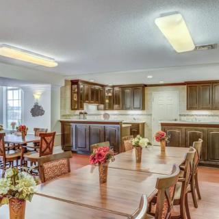 A cozy kitchen and dining area with wooden tables and chairs, decorated with floral centerpieces.