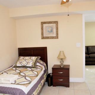 A small bedroom with a single bed, nightstand, and lamp.