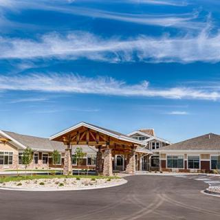 A modern care facility with landscaped surroundings under a clear blue sky.