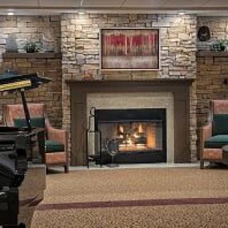 A cozy living room with a stone fireplace, comfortable armchairs, and warm decor.