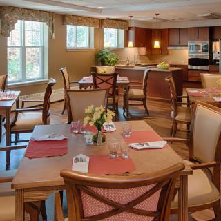 Elegant dining area with neatly arranged tables and chairs adjacent to a modern kitchen.