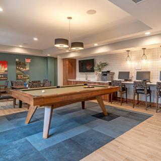 A modern game room featuring a pool table and lounge area with computers and stylish lighting.