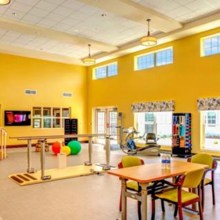 A brightly lit rehabilitation center featuring various therapy equipment and seating areas.
