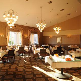 An elegant restaurant dining room with chandeliers and natural light streaming in.