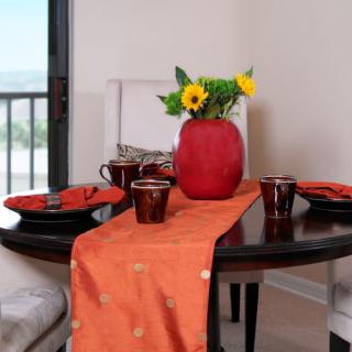 A beautifully set dining table with orange accents and a vase of sunflowers as the centerpiece.