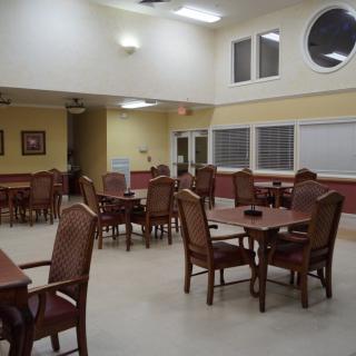 An empty dining room with arranged tables and chairs under bright lighting.