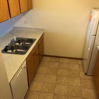 A compact kitchen with wooden cabinets, a sink, and tiled flooring.
