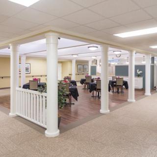 A cozy indoor dining area with multiple tables and chairs, surrounded by decorative columns.