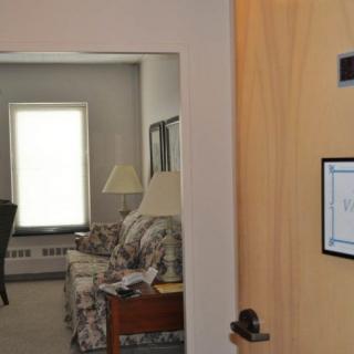 A view into a living room through an open door, showcasing furniture and natural light from a window.