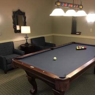 A cozy billiard room featuring a pool table with accompanying furniture and decor.