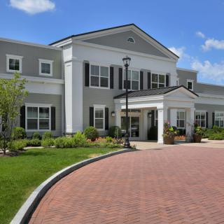 A large building with a welcoming entrance surrounded by well-maintained landscaping and a curved driveway.