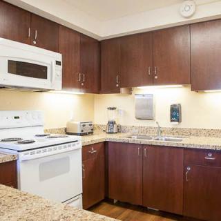 A modern kitchen with wooden cabinets, granite countertops, and various appliances.