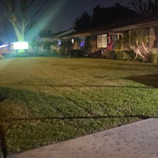A well-maintained lawn illuminated by nighttime lights in a residential area.