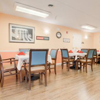 A cozy dining room with neatly arranged tables and chairs, adorned with wall art and warm lighting.