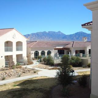 A serene view of a courtyard surrounded by buildings, with mountains in the background under a clear blue sky.