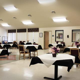 A well-lit dining room with neatly arranged tables and chairs.