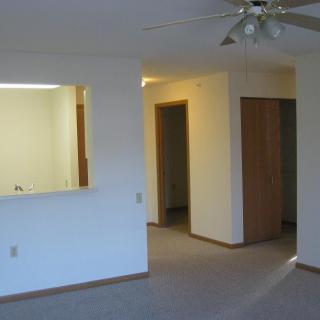 An unfurnished apartment interior with a ceiling fan and doorways leading to other rooms.