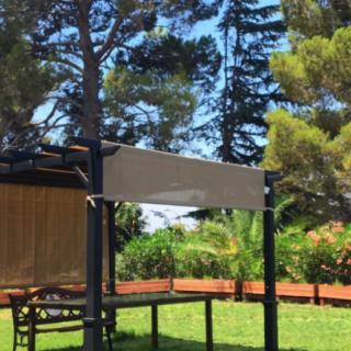 A tranquil outdoor gazebo surrounded by lush greenery on a sunny day.