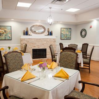 A cozy dining room with neatly arranged tables and a fireplace.