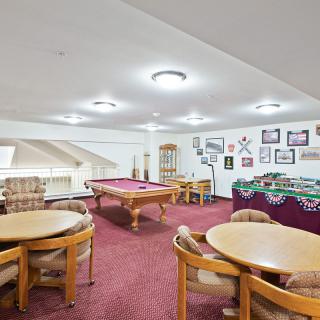 A cozy game room featuring a pool table, foosball table, and ample seating.