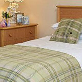 A cozy bedroom with plaid bedding and wooden furniture.