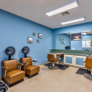 Interior of a barbershop with chairs, mirrors, and hairdryers.