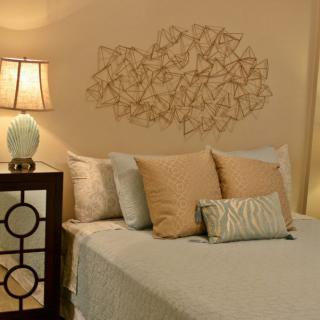 A cozy bedroom with a neatly made bed, decorative pillows, and ambient lighting.