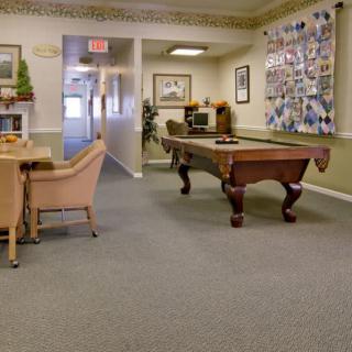 A recreation room featuring a pool table, surrounded by comfortable seating and decorated walls.